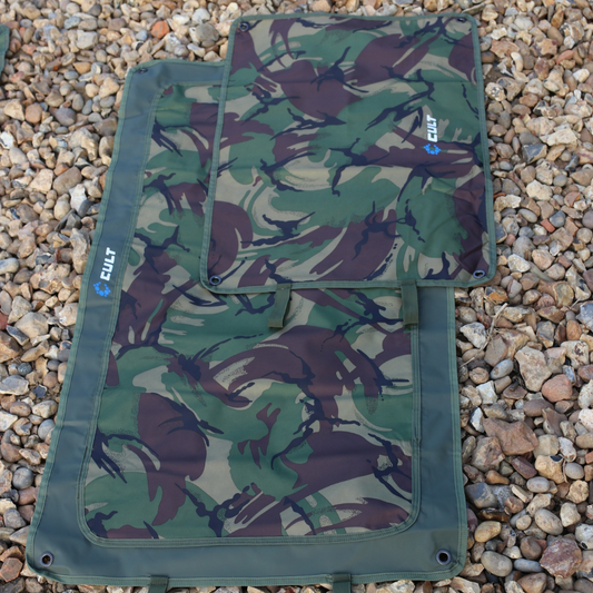 Camouflage-patterned mat with Cult branding on a gravel surface