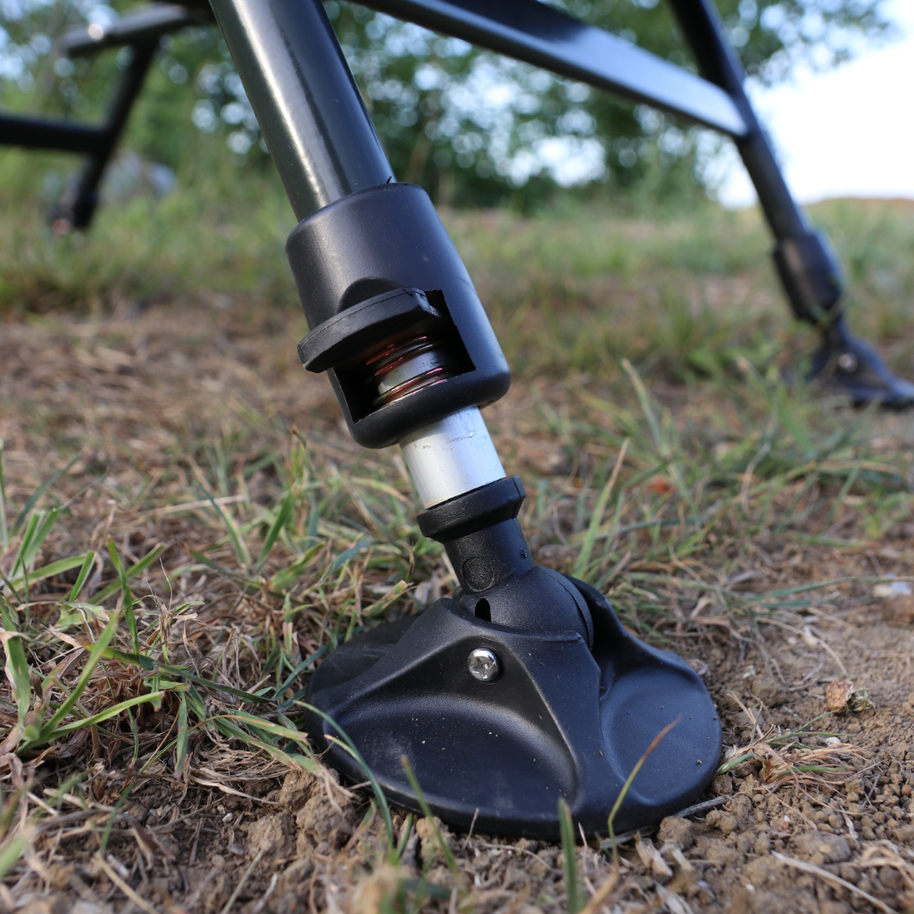 Close-up of a black metal rod with a wheel-like attachment on grass